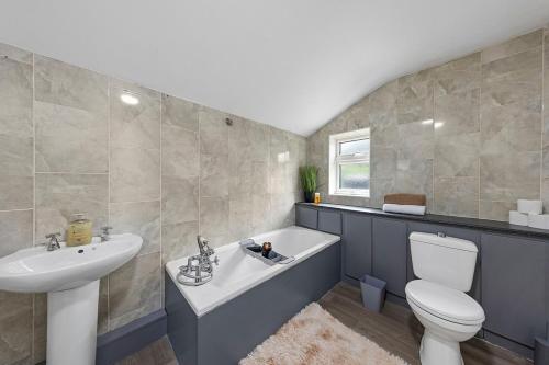 a bathroom with a sink and a tub and a toilet at Cosy 3-bed House Free Parking and Hot tub in Chatham