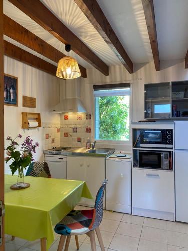 une cuisine avec une table et une table verte et des chaises dans l'établissement l'ESCALE, à Saint-Pair-sur-Mer