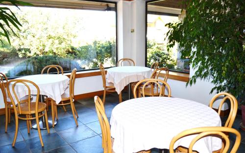 two tables and chairs in a restaurant with a window at Hotel Canturio in Cantù