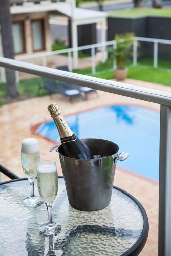 a bottle of champagne in a bucket on a table with glasses at Nightcap at the Ship Inn in Busselton