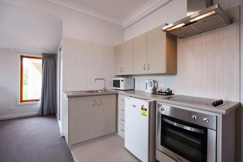 a kitchen with a sink and a stove top oven at Nightcap at the Ship Inn in Busselton