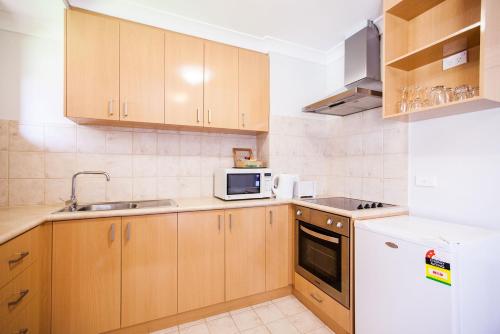 a kitchen with wooden cabinets and a white refrigerator at Nightcap at the Ship Inn in Busselton