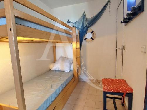 Cette chambre comprend 2 lits superposés et une chaise. dans l'établissement Studio cabine en rez de jardin dans residence avec piscine, à Sète