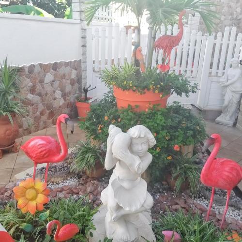 a statue of a girl in a garden with flamingos at Studio de charme à Bouillante, 100 m², vue sur mer et montagnes in Bouillante