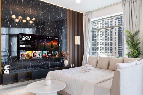 a living room with a white bed and a tv at Beautiful 2 BR Apartment next to Opera I Burj View in Dubai