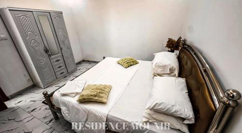 a bedroom with a bed with two pillows on it at Résidence Mounir in Thiès