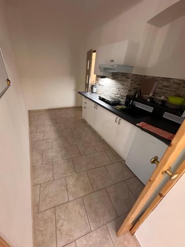 Una cocina con gabinetes blancos y piso de baldosas. en Ubytování u Šimků, en Broumov
