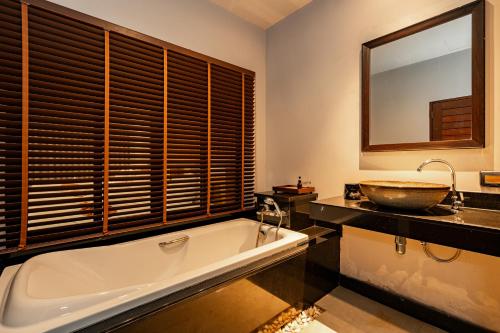a bathroom with a large tub and a sink at Malabar Pool Villa Phuket in Phuket Town