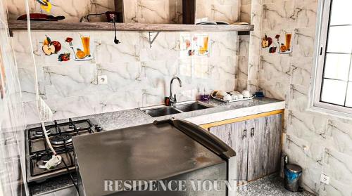 a kitchen with a sink and a stove at Résidence Mounir in Thiès