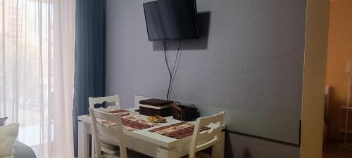a dining room table with a cake and a tv on the wall at Vake Residence close to Park Mziuri in Tbilisi City
