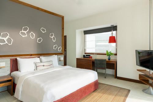 a bedroom with a bed and a desk and a television at Dhigali Maldives - A Premium All-Inclusive Resort in Raa Atoll