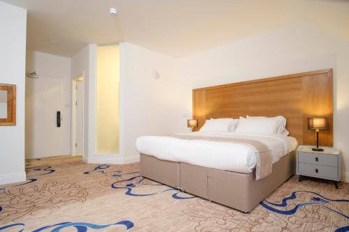 フォルカークにあるKelpies Hotel Falkirkの木製のヘッドボードが付いた大きなベッドのある寝室