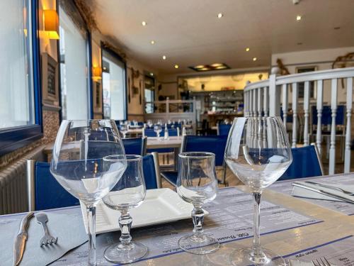four wine glasses sitting on top of a table at Au Ptit Mousse - Hôtel et Restaurant in Courseulles-sur-Mer