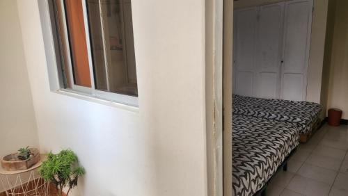 a room with a bed with a window and a door at Meeting Point Praia-QC Beachwalk, also in Tarrafal & Fogo-NO CASH ACCEPTED in Praia