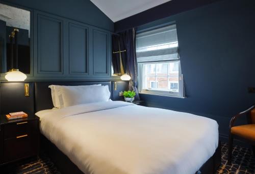 a large white bed in a blue room with a window at The Mayfair Townhouse - an Iconic Luxury Hotel in London