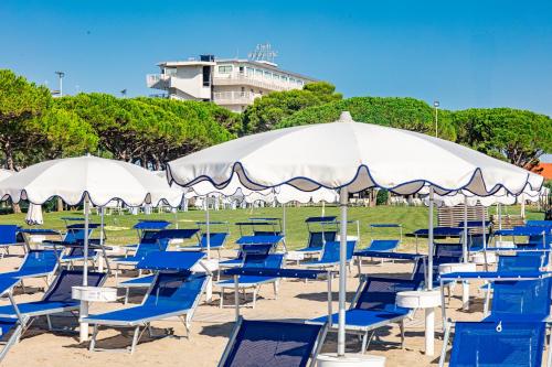 a bunch of chairs and umbrellas on a beach at Hotel San Giorgio Resort 4S in Caorle
