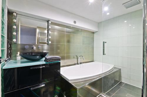 La salle de bains est pourvue d'une grande baignoire et d'un lavabo. dans l'établissement Superb Apartment Quartier Bonne Nouvelle Free Netflix, à Paris