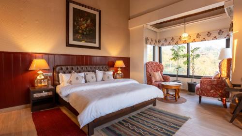 a bedroom with a bed and a chair and a window at Chakk 109 Mussoorie Foothills, Dehradun in Dehradun