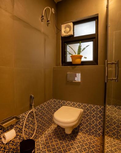a bathroom with a toilet and a window at Chakk 109 Mussoorie Foothills, Dehradun in Dehradun