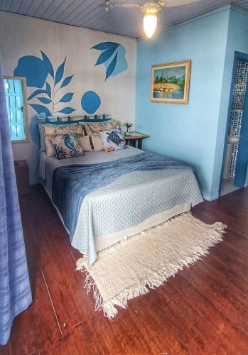 a bedroom with a bed with blue walls and a rug at Pousada Vida Simples in São Francisco do Sul