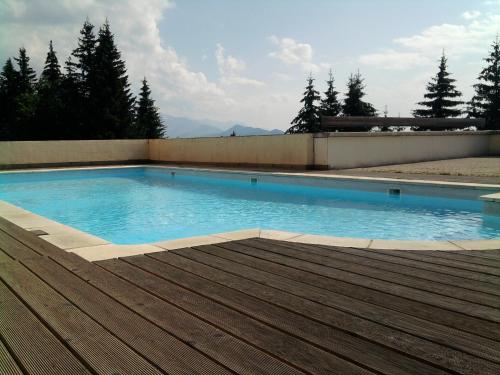 une piscine d'eau bleue et une terrasse en bois dans l'établissement Appartements Le Clos des Gentianes, à Allevard
