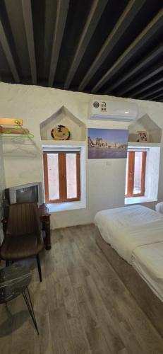 a bedroom with a bed and a desk and two windows at Riad Nizwa in Nizwa