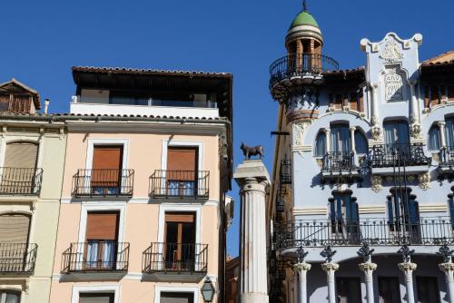 un grupo de edificios con balcones y una torre en Apartamentos Plaza del Torico Teruel, en Teruel