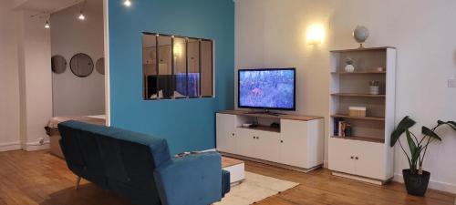 Il comprend un salon doté d'une télévision et d'un mur bleu. dans l'établissement Le Petit Loft de Saint Herem, à Clermont-Ferrand