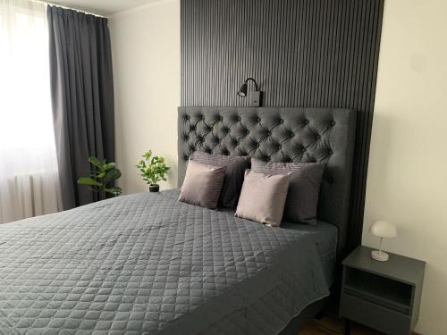 a bedroom with a large bed with a gray headboard at Leola Apartment in Viljandi