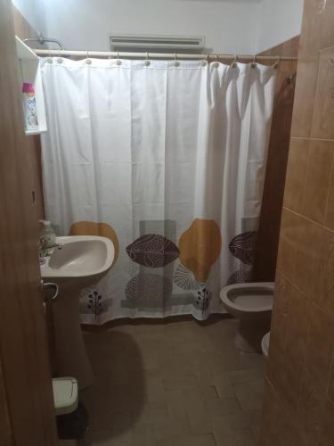 a bathroom with a sink and a toilet and a shower curtain at Casa Céntrica in Cosquín