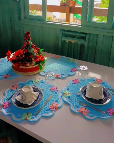 a table with two tea sets and a christmas tree on it at Pousada Vida Simples in São Francisco do Sul