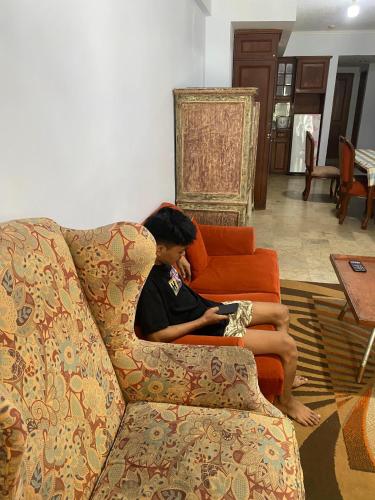 a man is sitting on a couch with his legs on a couch at KRK 1 - Kondominium Anyer Carita in Carita