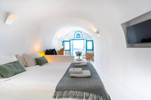 a white living room with a couch and a tv at Nano Oia Villas in Oia