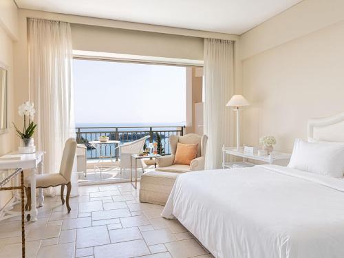 a hotel room with a bed and a balcony at Grecotel Eva Palace in Kommeno