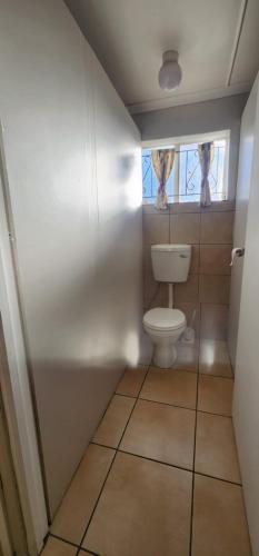 a small bathroom with a toilet and a window at Tesselaarsdal Backpackers & Koshuis in Caledon