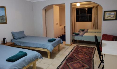 a small room with two beds and a rug at Tesselaarsdal Backpackers & Koshuis in Caledon