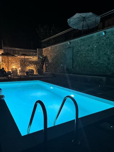 a blue swimming pool at night with an umbrella at Achlades The Mountain Paradise Villas - Studio with pool! in Aletrouvárion
