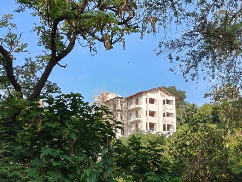 a tall white building in the middle of trees at Chakk 109 Mussoorie Foothills, Dehradun in Dehradun