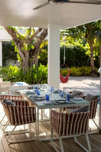 a table with chairs sitting on a patio at Dhigali Maldives - A Premium All-Inclusive Resort in Raa Atoll