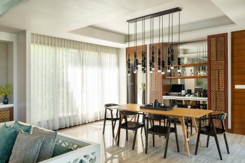 a dining room and living room with a table and chairs at Dhigali Maldives - A Premium All-Inclusive Resort in Raa Atoll