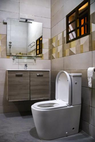 a bathroom with a toilet and a sink and a mirror at Stylish 2BR Modern Apt in Cité Baguida in Lomé