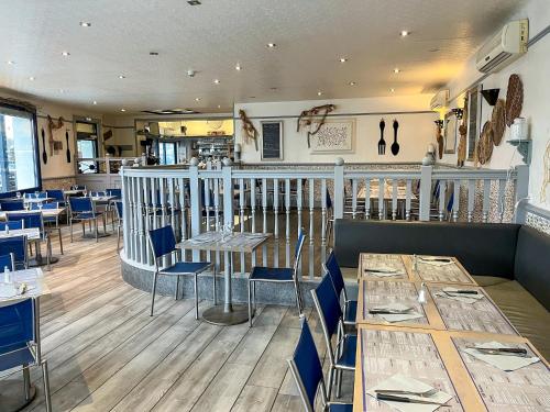a restaurant with tables and chairs in a room at Au Ptit Mousse - Hôtel et Restaurant in Courseulles-sur-Mer
