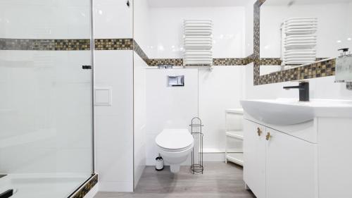a white bathroom with a toilet and a sink at Grunwaldzka, Sun & Snow in Pobierowo