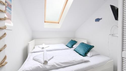 a white bed in a white room with blue pillows at Grunwaldzka, Sun & Snow in Pobierowo