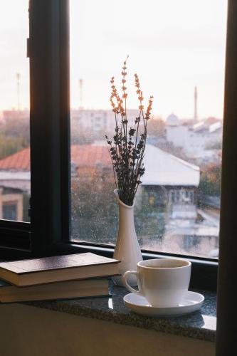 a vase and a cup and a book on a window at Parklane Hotel in Tashkent
