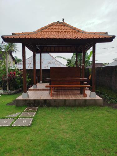 a wooden gazebo with a bench in a yard at Borneo Log Cabin Guest House in Buleleng