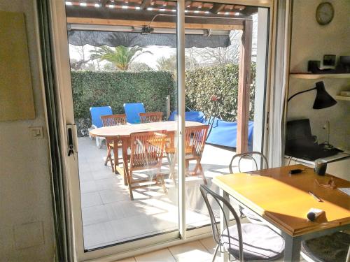d'une terrasse avec une table, des chaises et une porte coulissante en verre. dans l'établissement Maison confortable à Le Barcarès 33 m² avec piscine partagée, au Barcarès