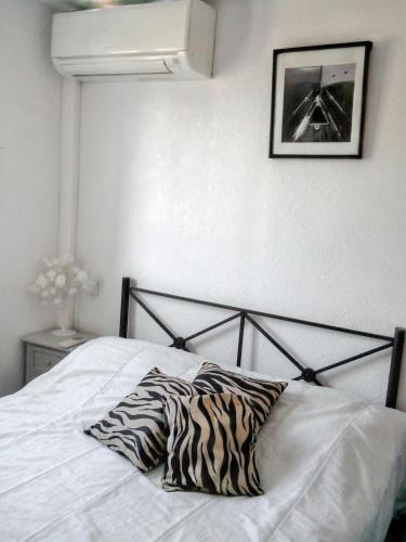 - un lit avec des oreillers zébrés dans une chambre dans l'établissement Maison confortable à Le Barcarès 33 m² avec piscine partagée, au Barcarès