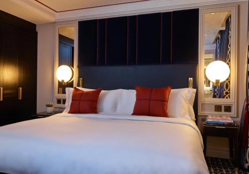 a bedroom with a large white bed with red pillows at The Mayfair Townhouse - an Iconic Luxury Hotel in London