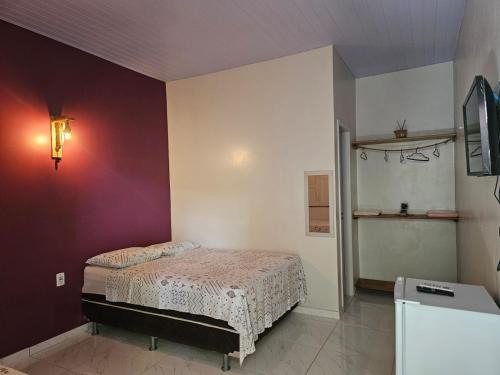 a bedroom with a bed and a purple wall at Casa do Ivo Pousadas - Vip Alter in Alter do Chao